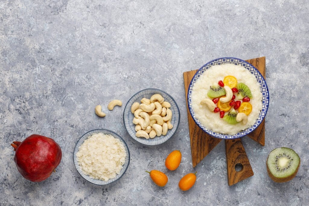 bowl rice flakes porridge with kiwi slices pomegranate seeds cumquats cashew nuts top view 1